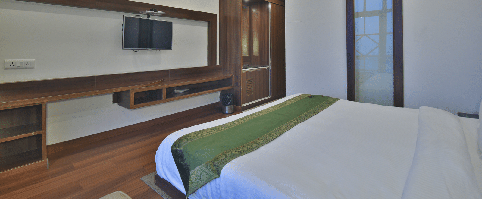 A view of the bed in front of a TV in a Premium Room at DLS Highland Resort and Spa, Mussoorie.
